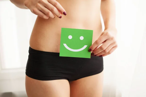 Salud de las mujeres. Primer plano de mujer sana con hermoso ajuste cuerpo delgado en bragas negras sosteniendo tarjeta verde con la cara sonriente feliz en las manos. Salud estomacal y buenos conceptos de digestión. Alta resolución — Foto de Stock