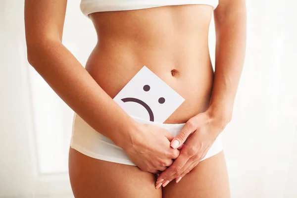 Salud de la mujer. Cuerpo femenino sosteniendo triste sonrisa tarjeta cerca del estómago — Foto de Stock