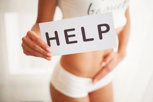 Saúde da mulher. Corpo feminino segurando símbolo cartão de ajuda perto do estômago — Fotografia de Stock