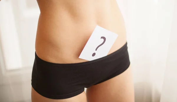 Salud. Mujer cuerpo en ropa interior con tarjeta de preguntas cerca del vientre — Foto de Stock