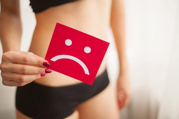 Zdraví ženy. Ženské tělo drží smutný úsměv kartu v blízkosti žaludku — Stock fotografie