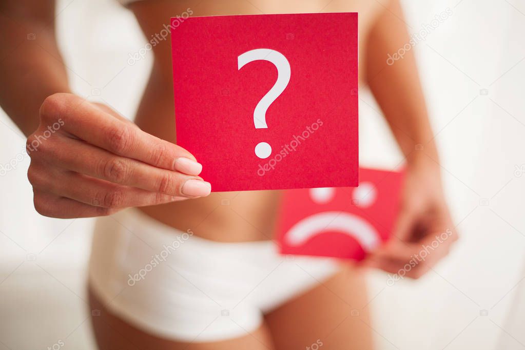 Woman Health Problem. Closeup Of Female With Fit Slim Body Holding Cards With Sad Smiley Face and Question Mark Near Her Stomach. Digestive Disorders, Period Pain, Health Issues Concept