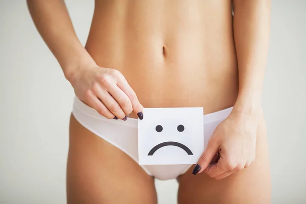 Salud de la mujer. Cuerpo femenino sosteniendo triste tarjeta sonriente cerca del estómago — Foto de Stock