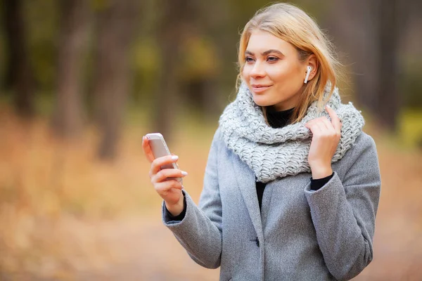 Joven mujer de belleza escuchando música en el parque de otoño — Foto de Stock