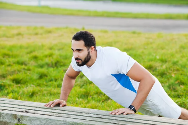 Fitness. Push-up exercise fitness man training arms muscles at outdoor gym.