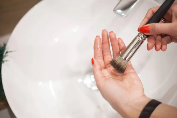 Makr fırça yukarıya. Kadın kirli makyaj fırça ile sabun ve köpük lavaboda yıkama