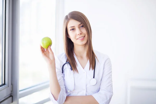 Diet. Happy medical doctor woman showing apple and stethoscope