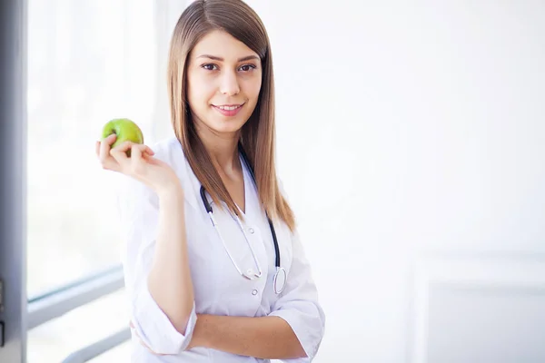 Diyet. Elma ve stetoskop gösterilen mutlu tıp doktoru kadın — Stok fotoğraf