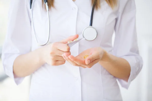 Médico segurando pílulas na mão. Conceito de medicina e cuidados de saúde — Fotografia de Stock