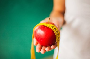 Diyet ve sağlık. Kırmızı elma ve santimetre bant eller içinde