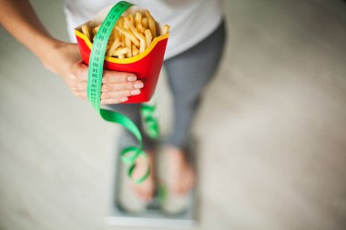 Diyet. Kadın vücut ağırlığı sağlıksız abur cubur tutan ölçek ağırlığında üzerinde ölçüm. Kilo kaybı. Obezite. Üstten görünüm