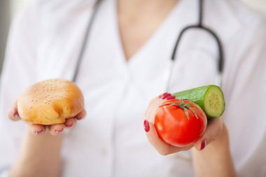 Diyet. Patty ve taze sebzeler arasında bir seçim veren doktor kadın portre