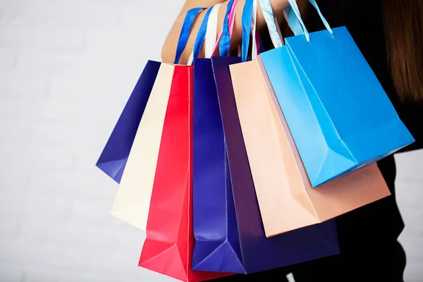 Shopping. Woman holding colored bags on light background in black friday holiday — Stock Photo, Image