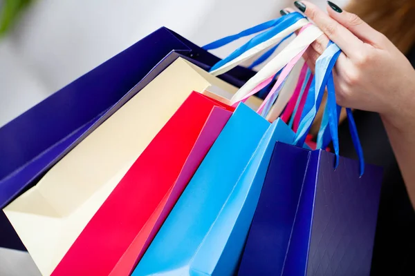 Faire du shopping. Gros plan de femme tenant sac à provisions en papier couleur sur fond mural blanc — Photo