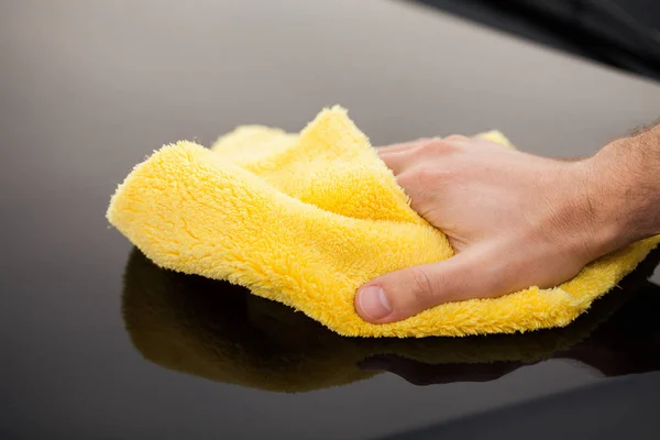 Limpiando coche. El hombre sostiene la microfibra en la mano y pule el coche — Foto de Stock