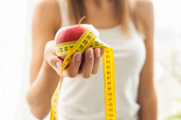 Dieta y salud. Manzana roja y cinta de centímetro en manos femeninas — Foto de Stock
