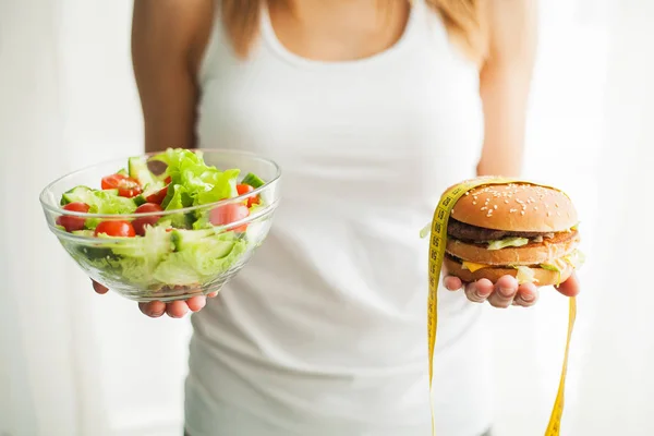 Дієта. Жінка вимірювання ваги тіла на кухонний комбайн проведення Burger і салат. Солодощі є нездоровий Junk Food. Дієти здорове харчування, способу життя. Втрата ваги. Ожиріння. Вид зверху — стокове фото