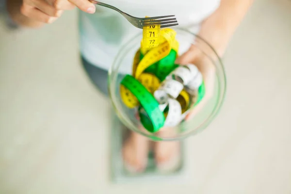 Diet and Weight Loss. Woman holds bowl and fork with measuring tape