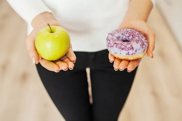 Δίαιτα. Γυναίκα μέτρησης σώματος βάρος για ζύγιση κλίμακας κρατώντας ντόνατ και μήλο. Τα γλυκά είναι ανθυγιεινά τρόφιμα παλιοπραγμάτων. Να κάνει δίαιτα, υγιεινή διατροφή, τον τρόπο ζωής. Απώλεια βάρους. Η παχυσαρκία — Φωτογραφία Αρχείου