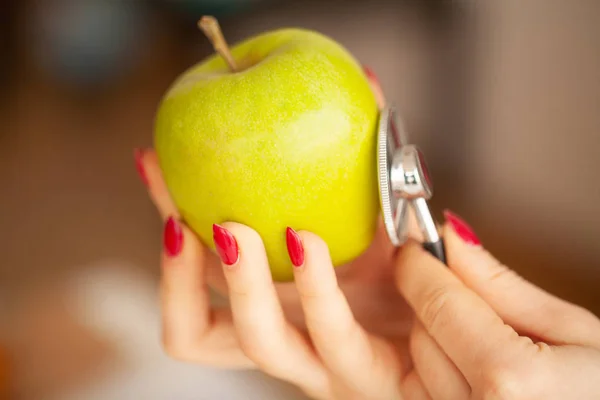 Hälsa. Porträtt av den lyckliga dietist i ljusa rum. Innehar den gröna äpplen och menyfliken Centimeter. Hälsosam kost. Färska grönsaker och frukter på bordet — Stockfoto