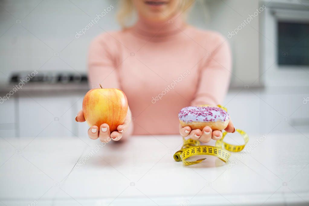 Dieting concept, beautiful young woman choosing between healthy food and junk food