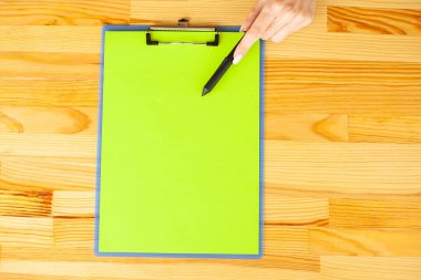 Bir klasörü bir yeşil renk kağıt ahşap masa arka plan üzerinde tutan office el. Boşaltmak. Metin için yer