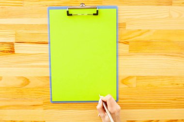 Bir klasörü bir yeşil renk kağıt ahşap masa arka plan üzerinde tutan office el. Boşaltmak. Metin için yer