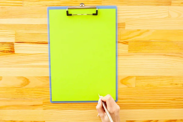 Bir klasörü bir yeşil renk kağıt ahşap masa arka plan üzerinde tutan office el. Boşaltmak. Metin için yer