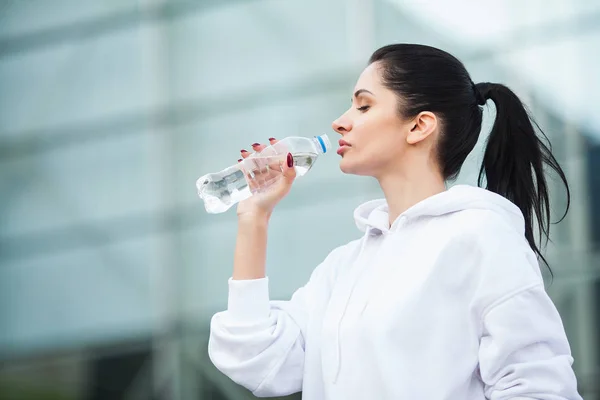 Фитнес на открытом воздухе. Женщина пьет бутылку воды — стоковое фото