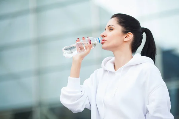 Фитнес на открытом воздухе. Женщина пьет бутылку воды — стоковое фото