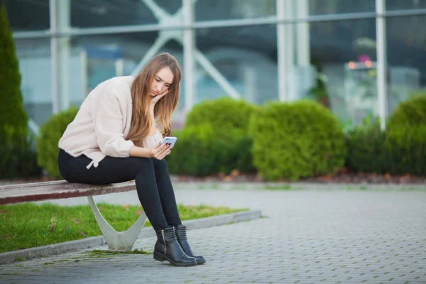 Mujer estresada por el trabajo mientras está sentada al aire libre, prensa de colegas — Foto de Stock