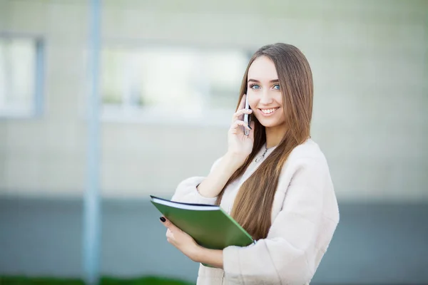 Mooie zakenvrouw buitenshuis. Jonge Glimlachende zakenvrouw met behulp van moderne smartphone buitenshuis — Stockfoto