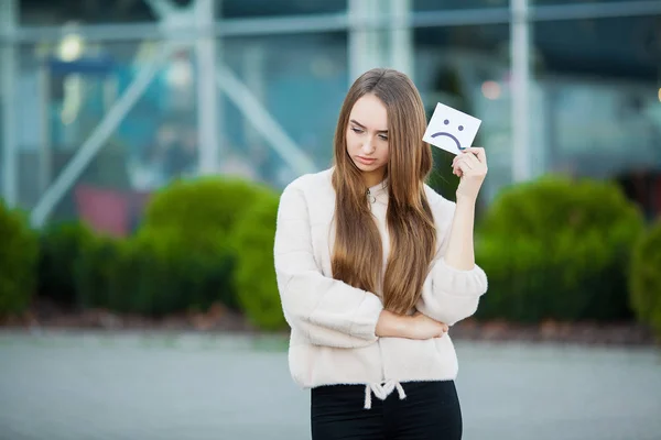 Beautiful woman holding card with sad smile — Stock Photo, Image