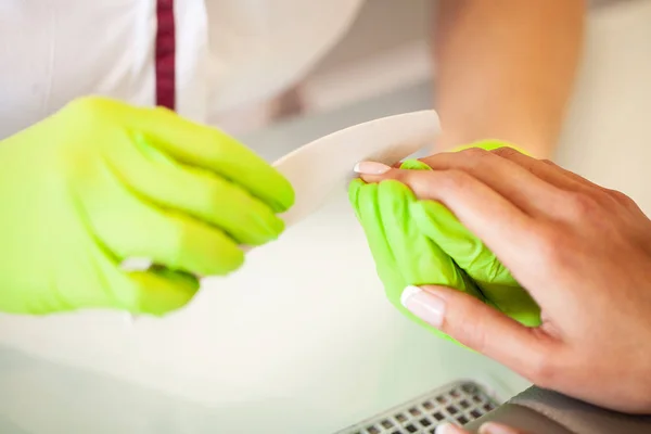 Manicure. Skillful master of manicure holding file in her hands while working in her beauty salon