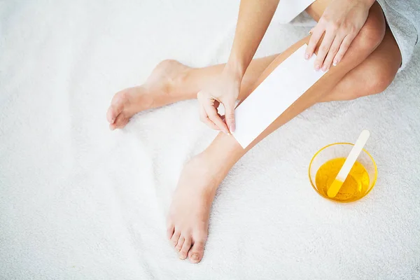 A encerar. jovem mulher depilação ela perna com cera listra — Fotografia de Stock