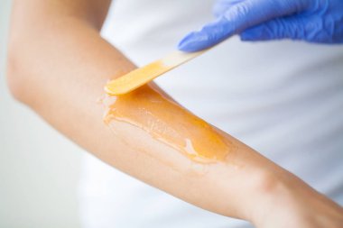 Usta, güzellik salonunda şeker yapıştırıcısının yardımıyla el sonlandırması yapıyor.