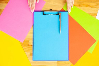 Bir klasörü bir mavi renk kağıt ve kalem ahşap masa renkli arka plan üzerinde tutan office el. Boşaltmak. Metin için yer