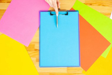 Bir klasörü bir mavi renk kağıt ve kalem ahşap masa renkli arka plan üzerinde tutan office el. Boşaltmak. Metin için yer