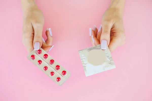 Pills or Condom. Antibiotics from venereal diseases. Concept of safe sex. Pills and condom lie on a pink Background