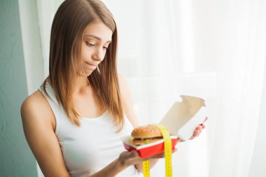Diyet. Kadın suçlu hissederek bir hamburger yemek