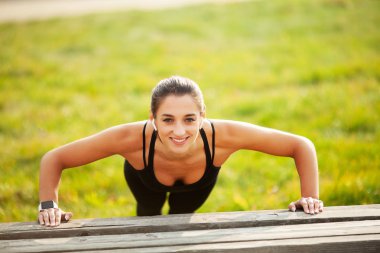 Fitness. Gün batımında tahta konumda açık havada duran atletik kadın. Spor, eğlence ve motivasyon kavramı