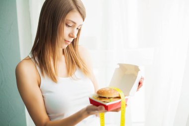 Diyet. Sağlıklı ve sağlıksız beslenme kavramı. Modeli artı boyutu yapar bir seçim sağlıklı gıda ve meyve lehine fast food ve burger reddederek