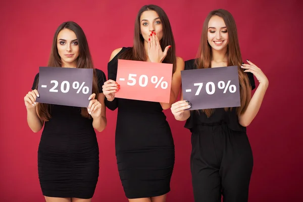 Shopping. Three women holding discount blank on red background in black friday holiday — Stock Photo, Image