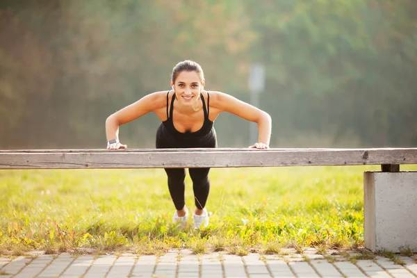 Fitness. Sportowe kobiety stojącej w deski pozycji na zewnątrz o zachodzie słońca. Pojęcie sportu, rekreacji i motywacja — Zdjęcie stockowe