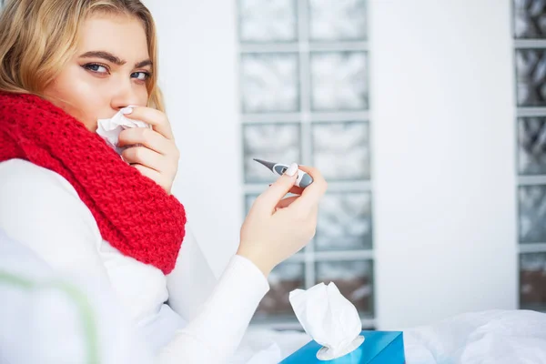 Kranke Frau. Frau mit Grippevirus liegt im Bett und misst ihre Temperatur mit Thermometer — Stockfoto