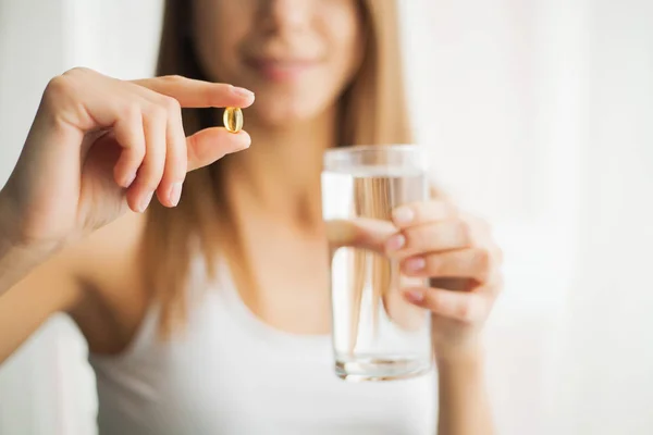 Happy smiling positive woman eating the pill and holding the glass of water in the hand, in her home — Stock Photo, Image