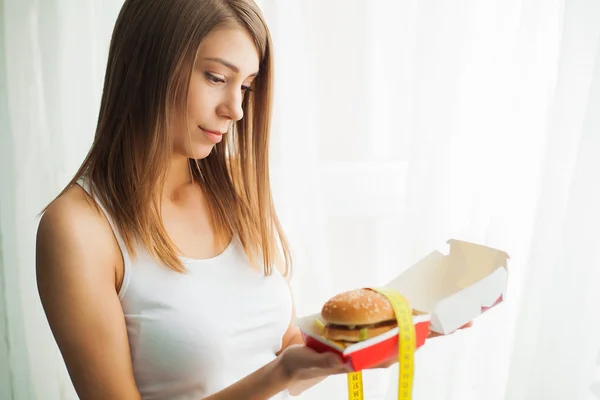 Diet. Woman with guilty feeling to eat a hamburger — Stock Image Diet. Woman with guilty feeling to eat a hamburger Stock Photo