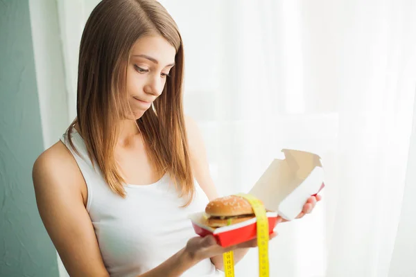 Diet. Woman with guilty feeling to eat a hamburger — Stock Image Diet. Woman with guilty feeling to eat a hamburger Stock Image