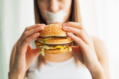 Diyet. Sağlıklı ve sağlıksız beslenme kavramı. Modeli artı boyutu yapar bir seçim sağlıklı gıda ve meyve lehine fast food ve burger reddederek