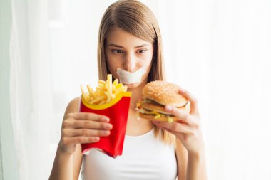 Diyet. Sağlıklı ve sağlıksız beslenme kavramı. Modeli artı boyutu yapar bir seçim sağlıklı gıda ve meyve lehine fast food ve burger reddederek
